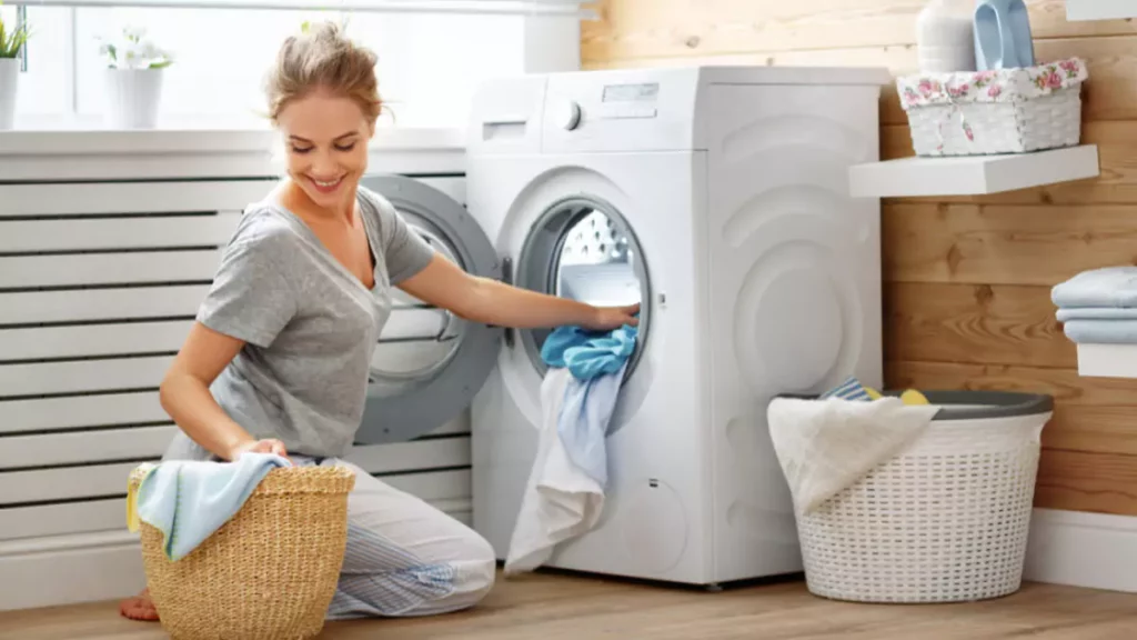 Mulher inserindo roupas sujas dentro de máquina de lavar e secar