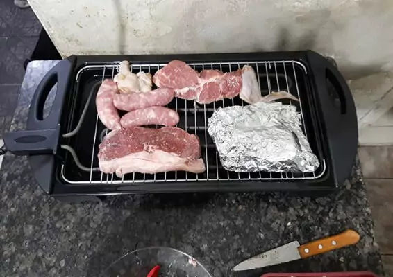 Fischer Grill em cima de bancada de mármore preto com carne bovina e suína
