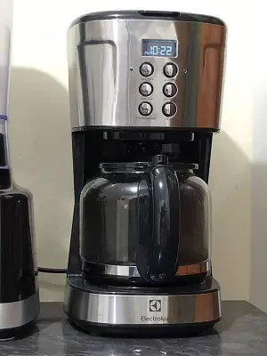 Electrolux ECM30 vista de frente em cima de balcão de mármore preto, com a jarra cheia de café e visor ligado.