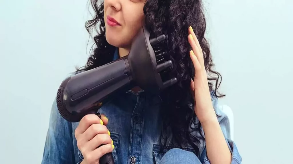 Abertura do post sobre como usar difusor de cachos: Mulher utilizando difusor em cabelo encaracolado