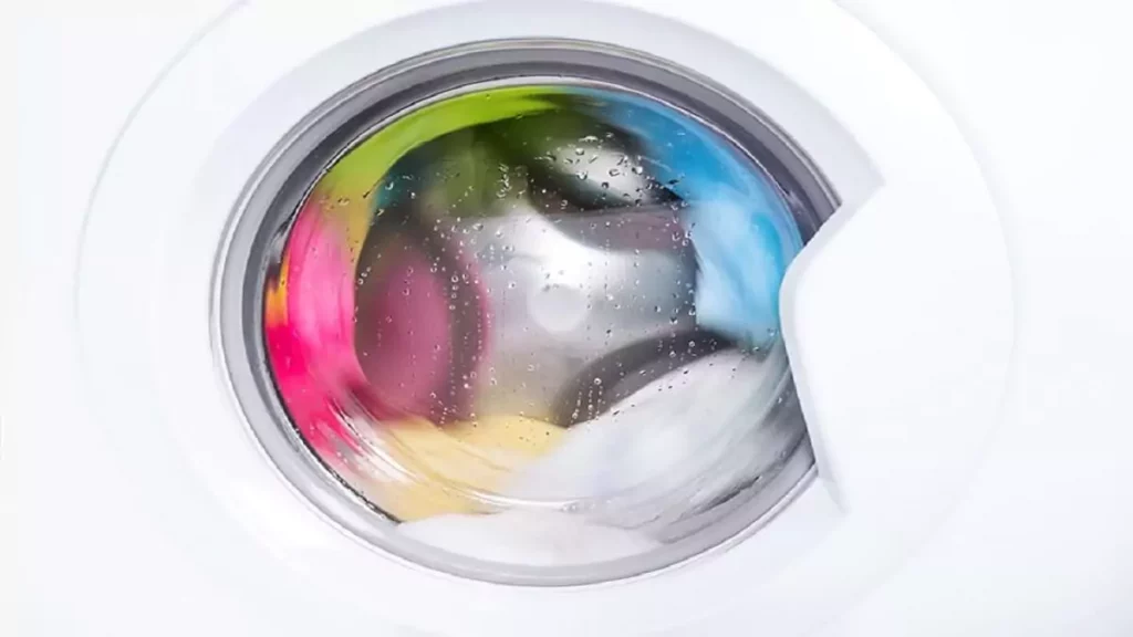 Abertura do post sobre o que é centrifugação na máquina de lavar: Lavadora front-load centrifugando roupas coloridas