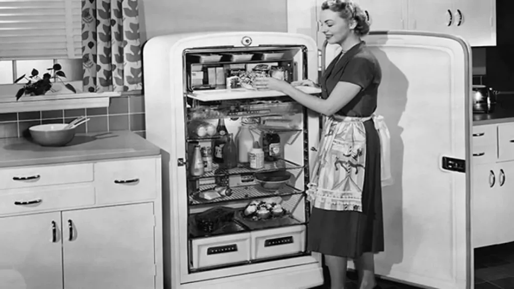 Abertura do post sobre quem inventou a geladeira: Mulher abrindo refrigerador antigo