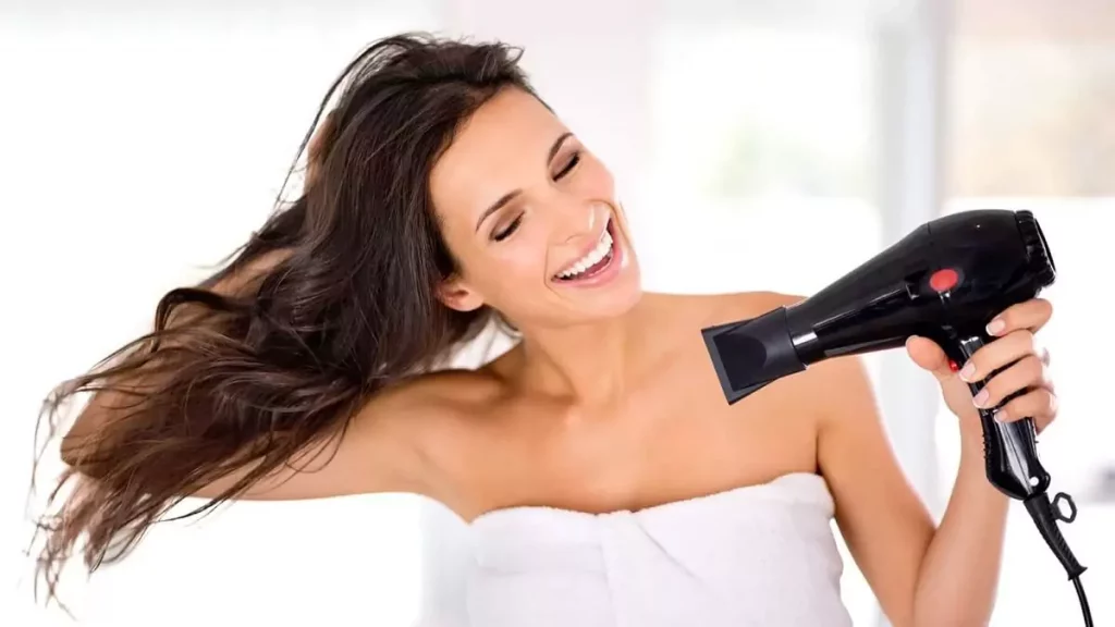 Abertura do post sobre como escolher secador de cabelo: Mulher feliz secando cabelo comprido