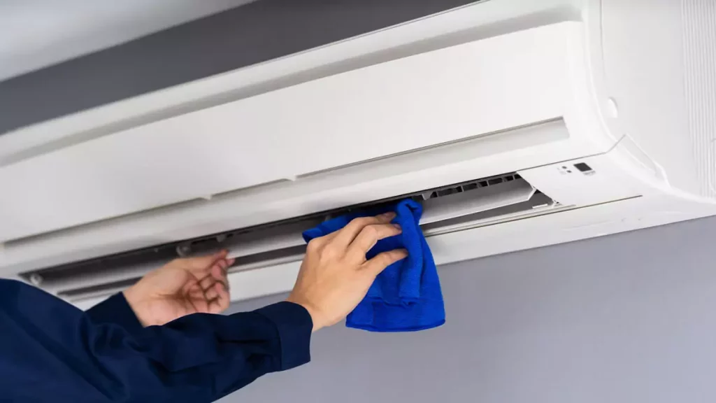 Pessoa limpando evaporadora de Ar Condicionado com flanela azul